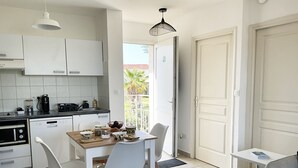 Eine moderne Küche mit weißen Schränken, einem Esstisch mit Stühlen und einer Kaffeemaschine.