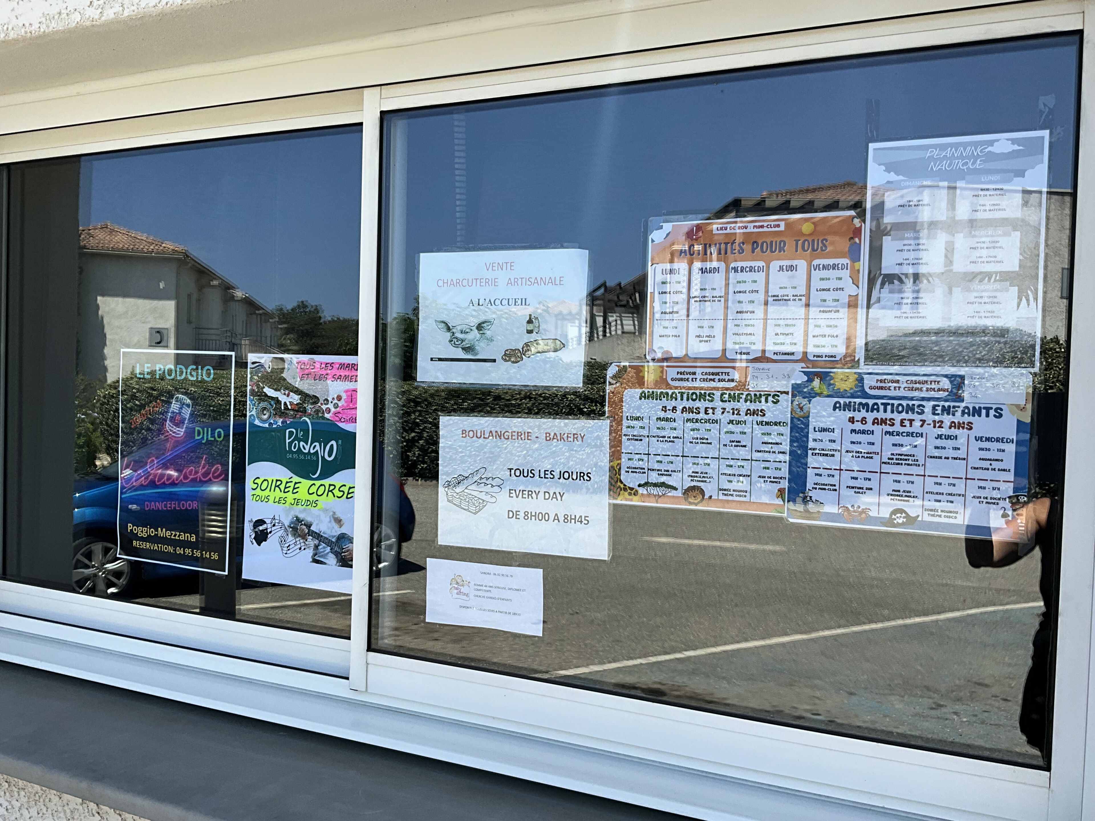 A window with various posters advertising local events and businesses, including a karaoke venue and a bakery.