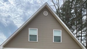 Ein zweistöckiges Haus mit Satteldach, zwei Garagentoren und einer kleinen Veranda.