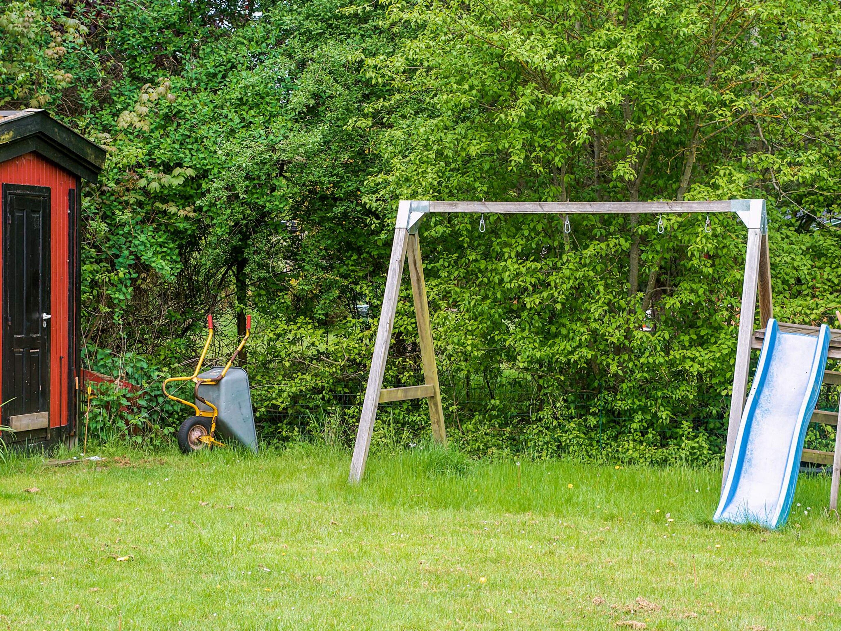 A playground with a swing set and a slide, surrounded by greenery.