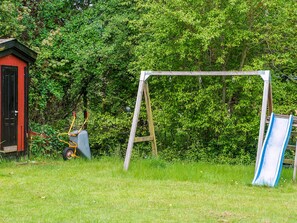 A playground with a swing set and a slide, surrounded by greenery. - 8 Person Holiday Home in Holbaek (Holbaek)