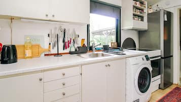 A compact kitchen with a built-in washing machine, a sink, and a window providing natural light.