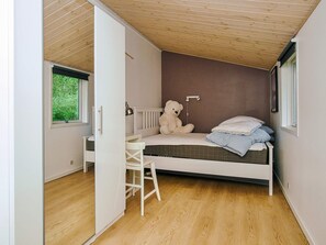 A bedroom with a bed, a chair, a window, and a teddy bear. - 8 Person Holiday Home in Holbaek (Holbaek)