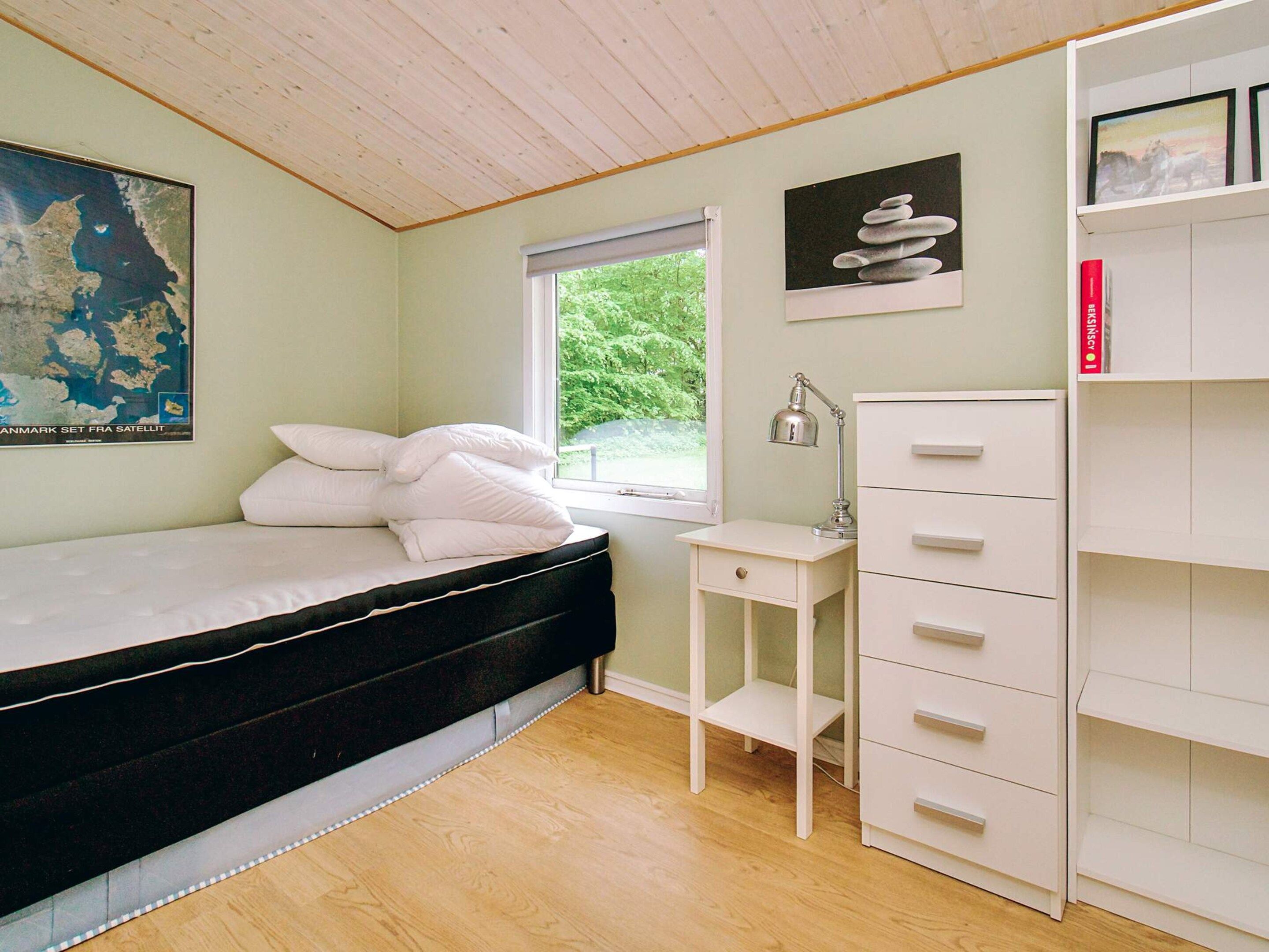 Una camera da letto con un letto, una scrivania, un comò e una finestra vista verde.