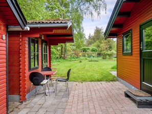 A red wooden house with a patio area featuring a table and chairs. - 8 Person Holiday Home in Holbaek (Holbaek)