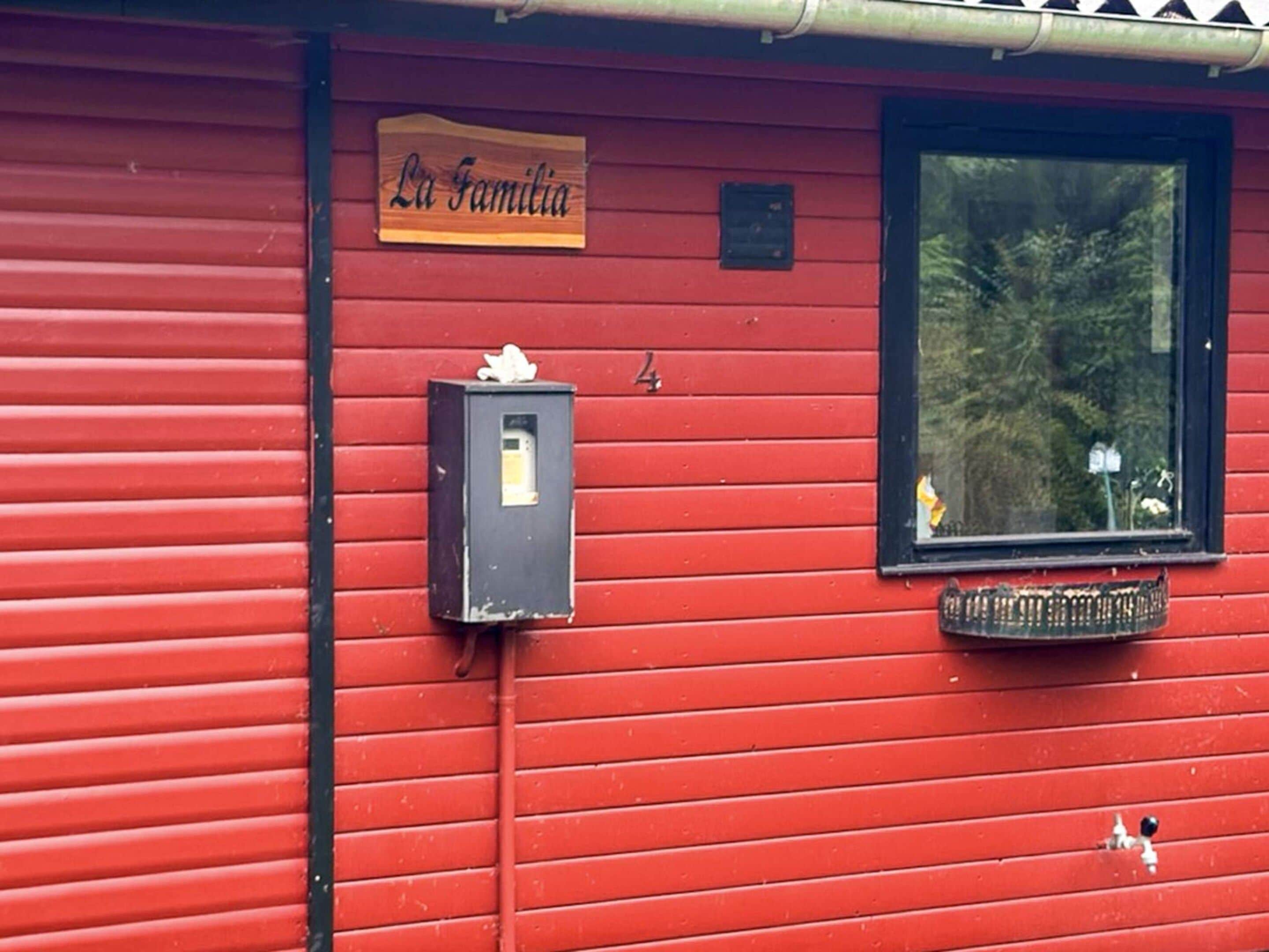 A red building with a wooden sign reading 'La Familia' and a mailbox.