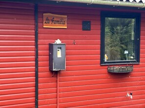 A red building with a wooden sign reading 'La Familia' and a mailbox. - 8 Person Holiday Home in Holbaek (Holbaek)