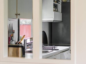 A kitchen with a sink, a dish rack, and a window with a red curtain. - 8 Person Holiday Home in Holbaek (Holbaek)