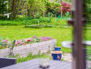 A garden with a wooden planter bed and a table with a cup. - 8 Person Holiday Home in Holbaek (Holbaek)