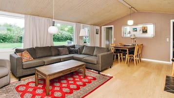 A modern living room with a sectional sofa, a wooden coffee table, and a red patterned rug.
