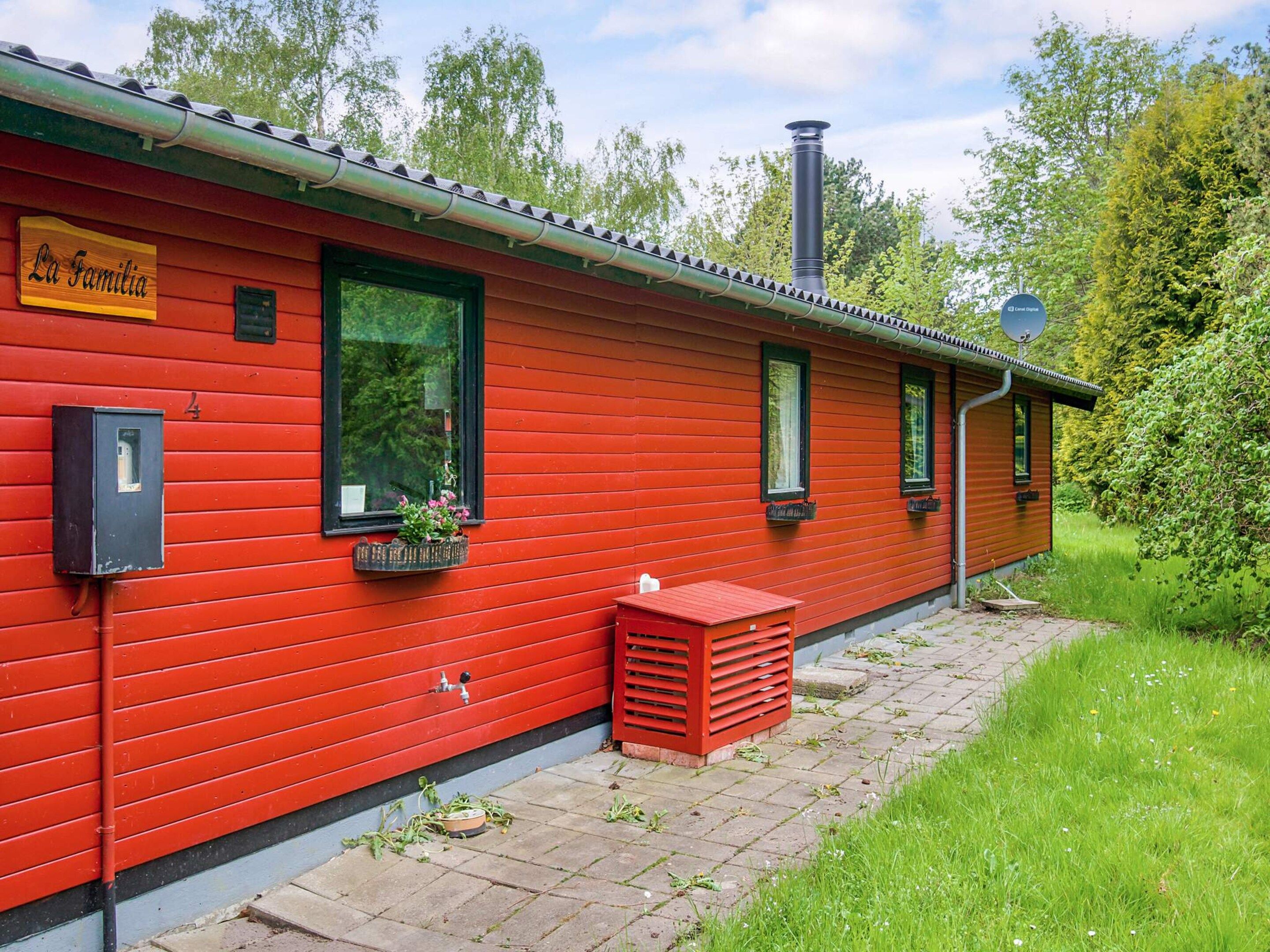Un edificio rojo con un letrero que dice 'La Familia', una ventana con una planta y una chimenea.