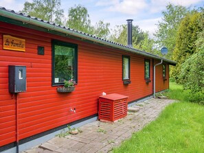 A red building with a sign reading 'La Familia,' a window with a plant, and a chimney. - 8 Person Holiday Home in Holbaek (Holbaek)