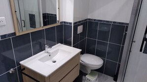 Une salle de bain avec un lavabo blanc, un meuble en bois et des toilettes.