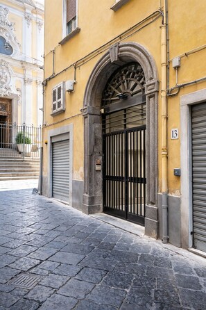 A building with a stone archway entrance, a closed metal gate, and a number '13' sign. - Piermeglio House. Apartment in the heart of the Historic Center of Naples (Napoli)
