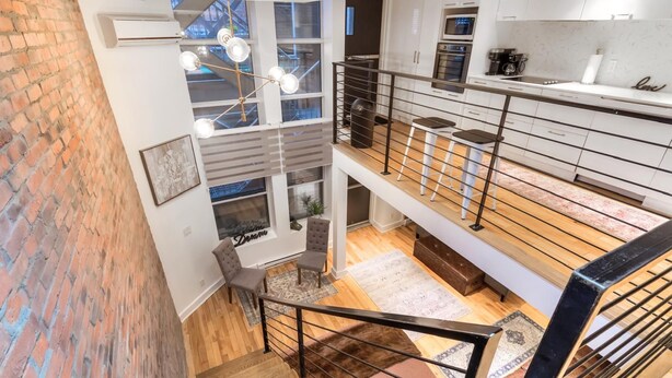 A multi-level apartment with a staircase, a kitchen, and a dining area.