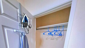 Una habitación con una puerta, una toalla a rayas, un perchero con colgadores azules y un suelo de color claro.