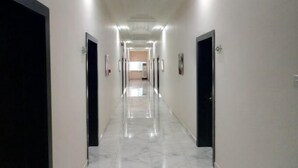 A long, well-lit hallway with marble flooring and black doors, leading to a room with a large window. - HOTEL SYLVIA (Enugu)
