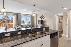 A modern kitchen with granite countertops, stainless steel sink, and a dishwasher. - Exquisite 2BR/2BA With Best Fireworks View In Baytowne (Miramar Beach)