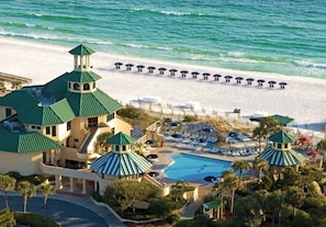 Un resort con piscina, sombrillas de playa y vista al mar.