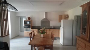 A spacious kitchen with a central island, wooden cabinets, and a dining area with a table and chairs.