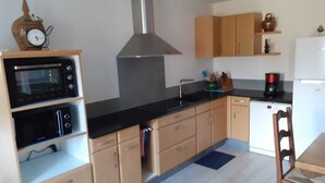 A compact kitchen with built-in appliances, wooden cabinets, and a small dining area.