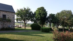 A stone building with a sloped roof, surrounded by a well-maintained lawn and trees.