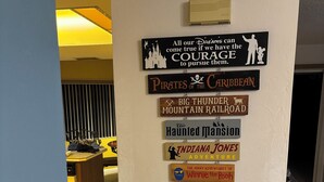 Una pared con varios letreros temáticos, incluyendo 'Pirates of the Caribbean' y 'Indiana Jones Adventure'.
