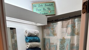 A bathroom with a toilet, sink, and stacked towels.