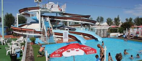 A pool area with a water slide and a lifeguard stand.