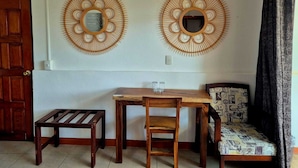 Ein Zimmer mit einem Holztisch, zwei Stühlen, einer Bank und zwei an der Wand befestigten dekorativen Spiegeln.