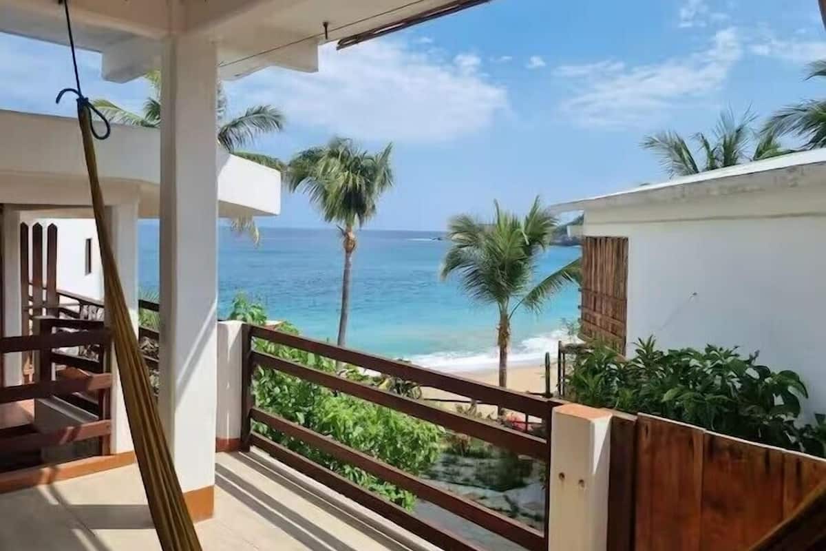 Un balcone con vista sull'oceano, ringhiera in legno e un oggetto appeso.