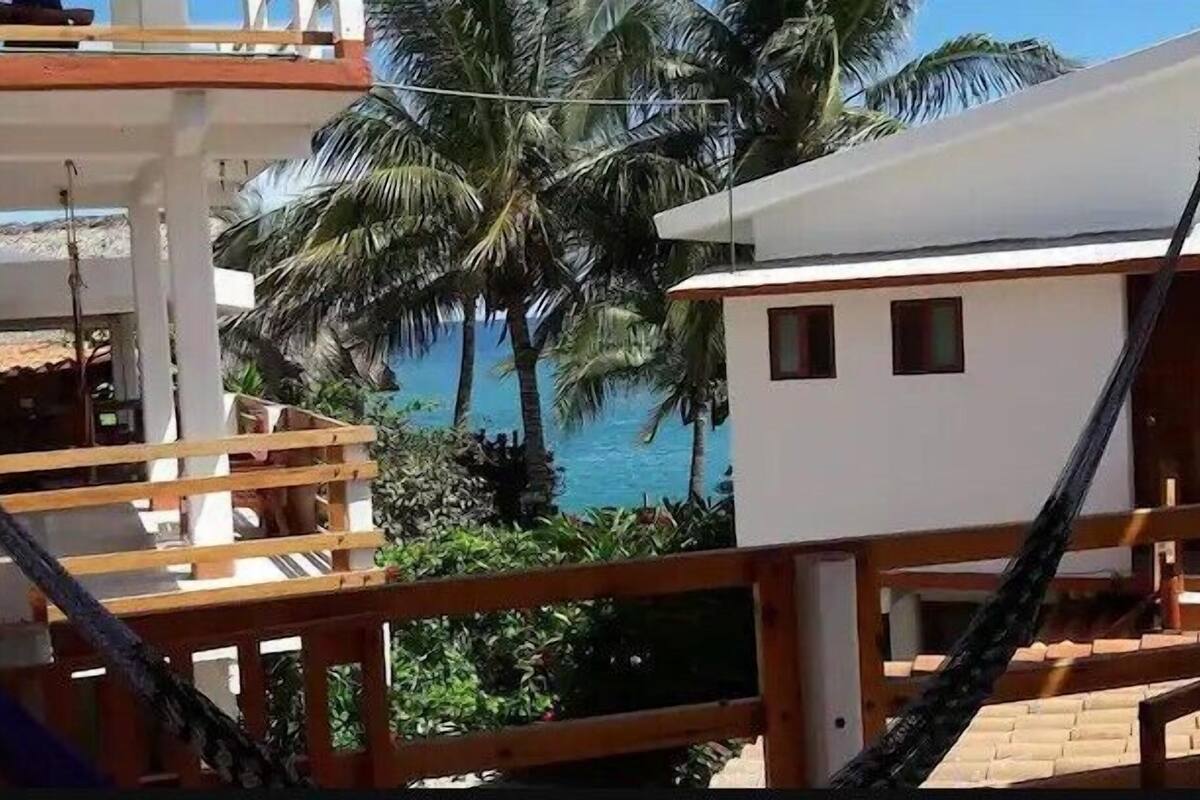 Una proprietà fronte spiaggia con una veranda in legno, un edificio bianco e palme.
