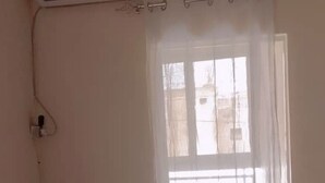Una habitació amb finestra, aire condicionat i una barra per a cortines.