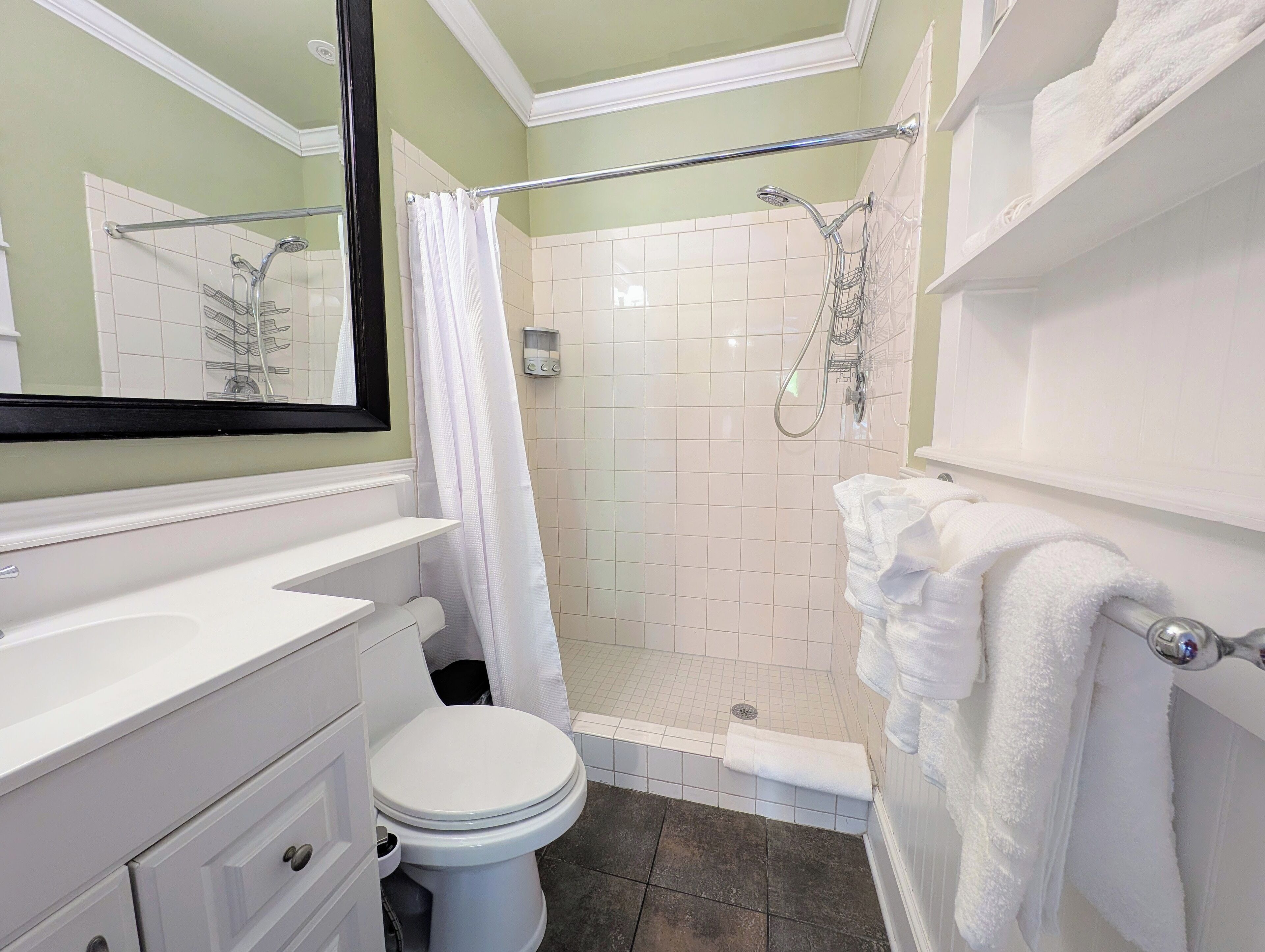 A bathroom with a white toilet, a shower with a glass door, a white sink, and a mirror above the sink.