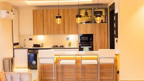 Una cocina moderna con armarios de madera, una isla central con taburetes de bar, un microondas integrado e iluminación colgante.
