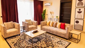 Una sala de estar moderna con un sofá, dos sillones, una mesa de centro y un tapete estampado.