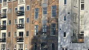 A row of multi-story buildings with balconies, a canal in the foreground, and a clear sky. - Luxury, Newly Remodeled Apartment in 16th Century Warehouse, with 10 meter Boat. (amsterdam)