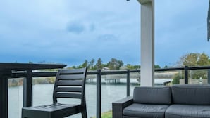 A balcony with a view of a body of water, a chair, and a sofa.