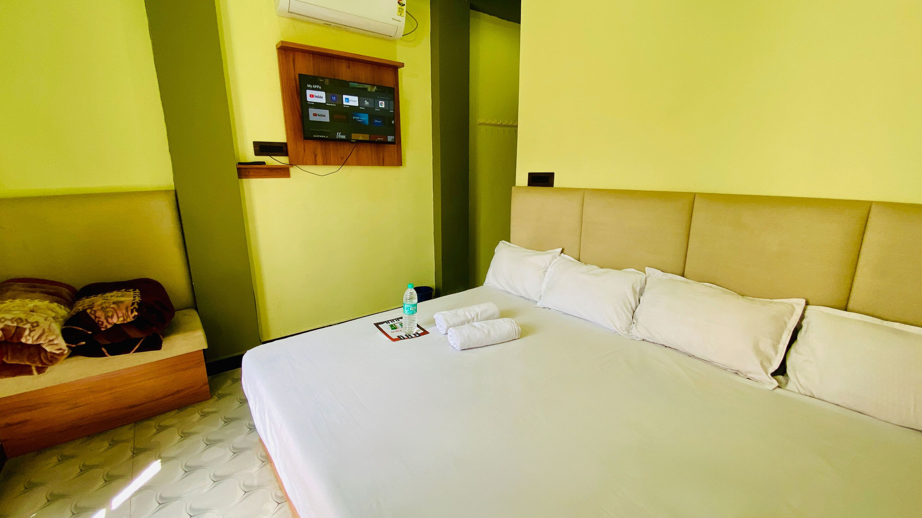 Une chambre d’hôtel équipée d’un lit, d’oreillers, d’une bouteille d’eau et d’un téléviseur fixé au mur, qui affiche différentes applications.