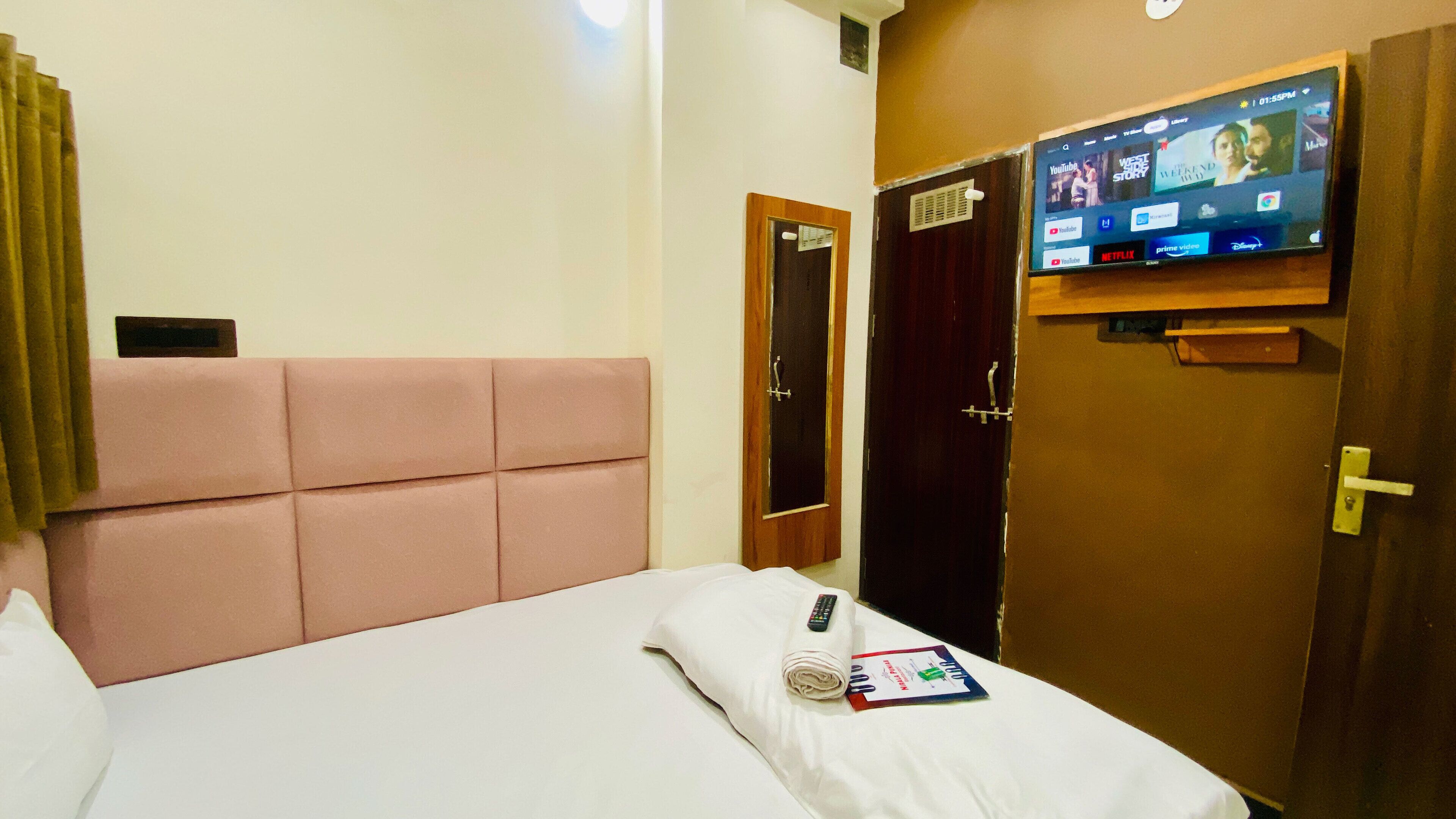 Une chambre d’hôtel avec un lit, un téléviseur fixé au mur et une porte.