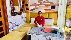 A room with a sofa bed, a marble-patterned table, and a wooden door.