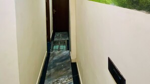 A hallway with a marble floor, a door at the end, and a mural of a forest scene on the wall.