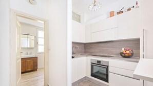 Een moderne keuken met witte kasten, een ingebouwde oven en een houten spatwand.
