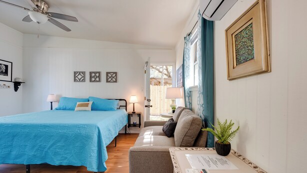 Une chambre à coucher avec un lit, un canapé, une petite table et un ventilateur de plafond.