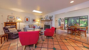 Amplia sala de estar con chimenea, comedor con mesa y sillas, y un ventanal con vistas al exterior.