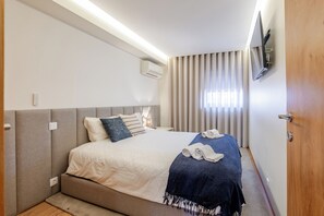 A bedroom with a bed, bedside tables, a TV, and a window with curtains. - Beachouse Pvz 🌊🌅 (Póvoa de Varzim)