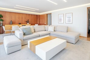 A modern living room with a sectional sofa, a wooden coffee table, and a white accent chair. - Beachouse Pvz 🌊🌅 (Póvoa de Varzim)