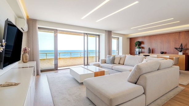 A modern living room with a large flat-screen TV, a sofa, a coffee table, and a view of the sea through large windows. - Beachouse Pvz 🌊🌅 (Póvoa de Varzim)