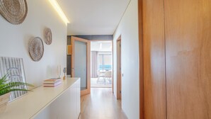 A hallway with a wooden door, a white counter with decorative plates, and a view into a dining area. - Beachouse Pvz 🌊🌅 (Póvoa de Varzim)