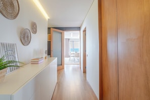 A hallway with a wooden door, a white counter with decorative plates, and a view into a dining area. - Beachouse Pvz 🌊🌅 (Póvoa de Varzim)